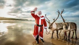 Father Christmas with two reindeer on the beach at Newquay, Cornwall
