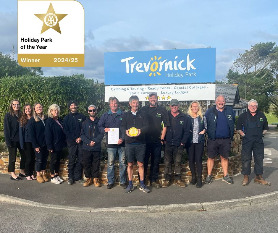 team trevornick stand outside the holiday park next to the entrance sign with their best holiday park of the year award