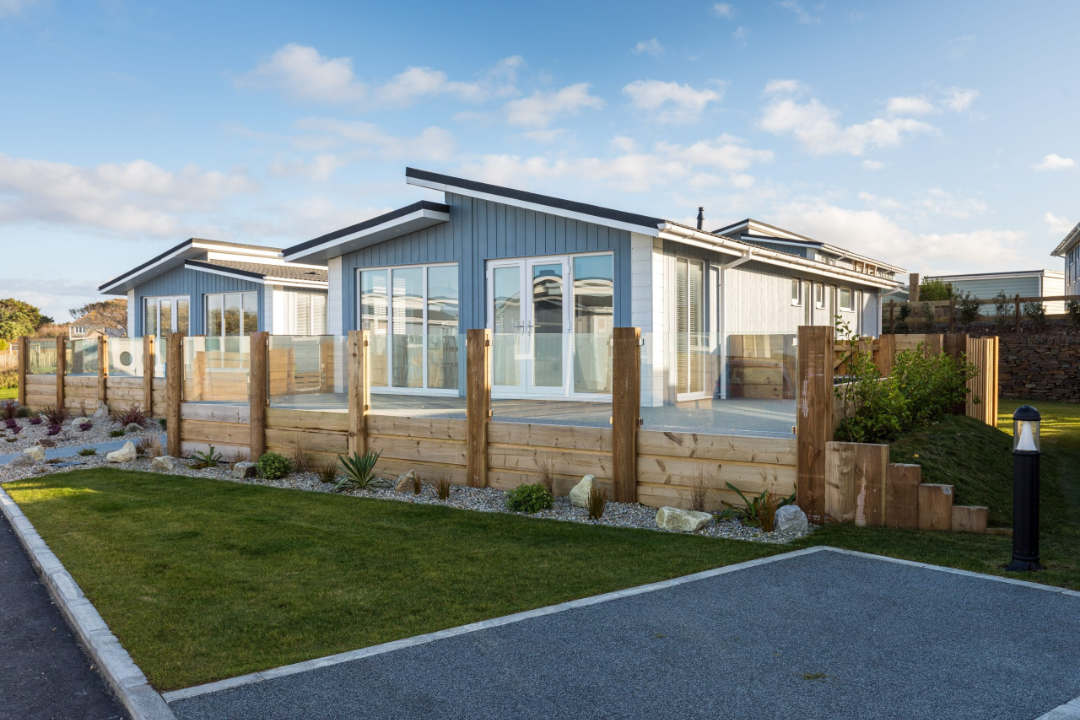 Modern luxury holiday lodge in Cornwall with glass-fronted decking and parking.